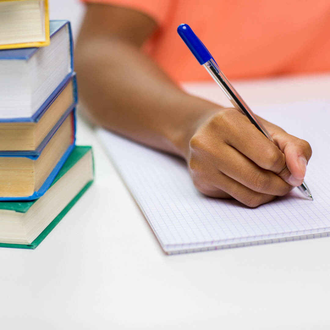 woman holding a pen writing descriptively in her notebook