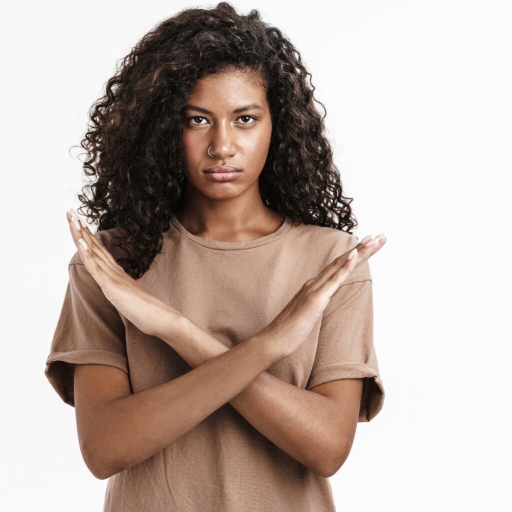 Black woman with long brown curly hair crossing her arms in an ex.