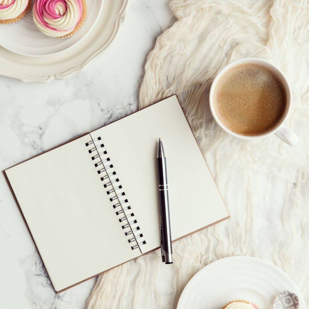 Mood tracking journal with gray pen and white cup of cocoa next to it.