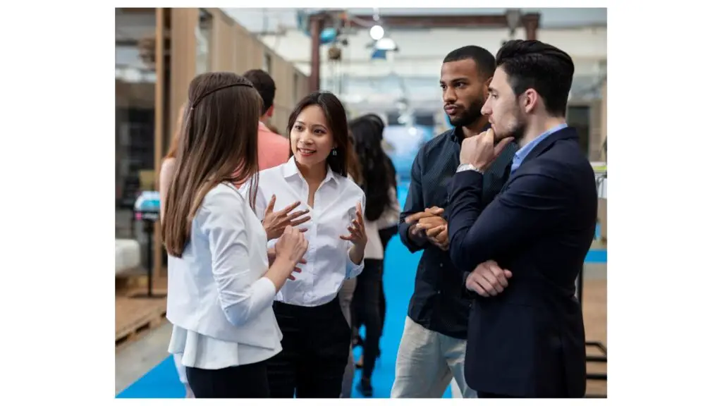 Two women networking across from curious men as they are intrigued by qualities of a good writer.