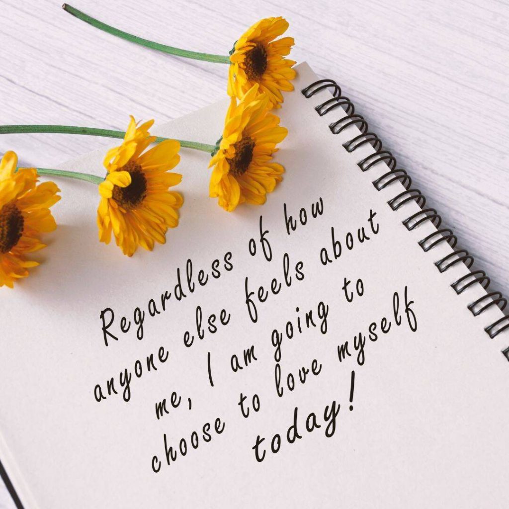 Inspirational quote written in black ink on white paper in spiral bind notebook with four live Sunflowers laying on top of the notebook.