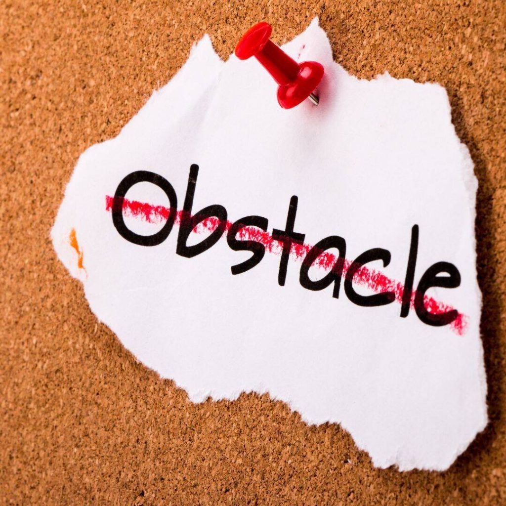 Obstacle written on uneven piece of paper with a red line drawn through it and pinned to a board.