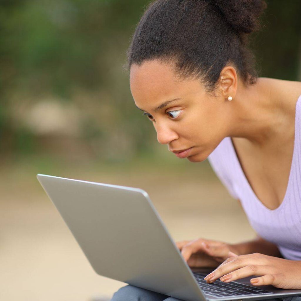 black woman staring intently and anxiously at her laptop.  She appears to be taking her journaling to the next level by journaling her biggest anxieties.