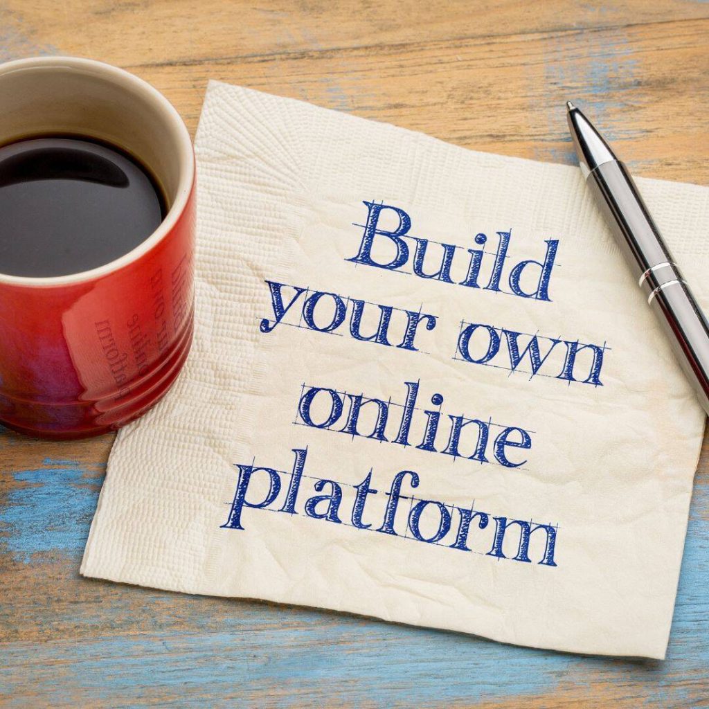 Build Online Pllatform written on napkin.  Red mug with coffee on table next to it.